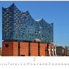 Aufschrift: "Elbphilharmonie". Ein modernes Gebäude mit wellenförmiger Glasstruktur auf einem alten Backsteinunterbau.