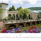 "Bad Kissingen, Kurpark" und "CASARES EDITION". Ein malerisches Gebäude am Wasser, umgeben von üppigem Grün und Blumen.