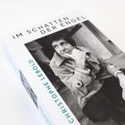 „IM SCHATTEN DER ENGEL“ und „CHRISTOPHE LEBOLD“ sind gedruckt. Schwarz-weiß Bild eines nachdenklichen Mannes.