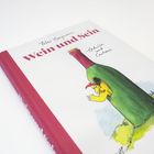 "Wein und Sein" steht auf einem Buchcover mit einer Illustration: eine Henne schaut aus einer Weinflasche.