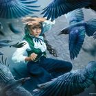 Eine Frau in historischer Kleidung schützt sich vor einer Schar anfliegender Krähen.