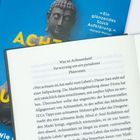 Text: "Was ist Achtsamkeit? Verwirrung um ein paradoxes Phänomen". Bücher überlagern sich, eins zeigt eine Buddha-Statue.