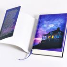 Ein aufgeschlagenes Buch, dessen Umschlag ein beleuchtetes Haus unter sternenklarem Himmel zeigt.