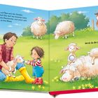 Links Text über Ella, Papa und Lämmer. Rechts ein Feld mit Schafen und Ziegen. Ella und ein Mann kuscheln mit Lämmern.