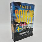 Titel: "Julimord" von Emelie Schepp. Ein rotes Haus an einer felsigen Küste, Himmel bewölkt.