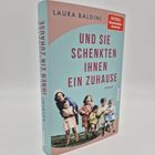 Buchtitel: "Und sie schenkten ihnen ein Zuhause" von Laura Baldini. Cover zeigt fröhliche, spielende Kinder.