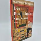 "Rachid Benzine. Der Buchhändler von Gaza. Roman." Illustration: Mann liest auf Bücherstapel sitzend.