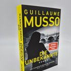 Cover: "Guillaume Musso - Die Unbekannte". Schattenriss einer Frau vor einer Brücke.