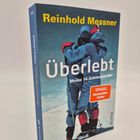 "Reinhold Messner. Überlebt. Meine 14 Achttausender. SPIEGEL Bestseller-Autor." Zwei Bergsteiger umarmen sich.