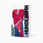 Text: "HUNDESOHN. OZAN ZAKARIYA KESKINCI. ROMAN. SUHRKAMP." 
Ein rot-weißes Shirt hängt über einem Stuhl.