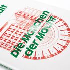 "Die Maschinen der Macht" steht in Grün. Zeichnung eines Gebäudes in Rot, zeigt architektonische Details.