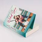 „Grace Reilly – Wicked Serve – Roman“. Ein Paar sitzt auf Treppen mit Hockeyschlägern und Volleyball, entspannt posierend.