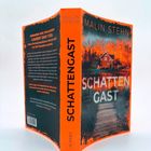 "Schattengast" von Malin Stehn. Auf dem Cover ein Haus umgeben von orangefarbenen Bäumen an einem ruhigen See.