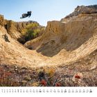 "2" und Kalendertage für Februar 2022. Radfahrer mit Helm springt in sonniger, felsiger Schlucht.