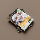 Zu sehen sind zwei übereinander liegende Bücher. Auf dem oberen Buch steht "UNTER GRUND". Eine Person trägt eine gestrickte Maske.