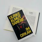BUCHCOVER: "ULRIKE ALMUT SANDIG IM ORKAN". Offenes Buch darunter, Kapitelüberschrift: "VII MAKSYM AUSATMEN".