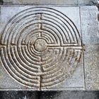 Rechter Text: "HIC AMICITVS CREATVS...". Relief eines Labyrinths mit kreisförmigen Mustern in einem steinernen Rahmen.