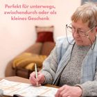 "Perfekt für unterwegs, zwischendurch oder als kleines Geschenk." Eine ältere Person löst ein Rätselbuch.