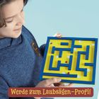 "Werde zum Laubsägen-Profi!" Ein Kind in blauem Pullover hält ein buntes Labyrinth-Spiel.