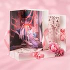 „Anna Savas hold me“ steht auf einem Buch. Eine Illustration zeigt ein Paar, umgeben von Lichterketten, auf rosa Hintergrund.