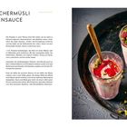 Blitz-Birchermüsli mit Beerensauce. Zwei Gläser mit rosa Joghurt, roter Sauce, Pistazien und Beeren auf schwarzem Tablett.
