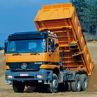 „Actros 3340“ und „RA-06020“. Ein orangefarbener Kipper mit angehobener Ladefläche auf einer Baustelle.