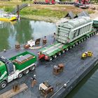 Lastdrager 32-3. Großer Schwerlasttransport auf einem Wasserfahrzeug mit grünem Lastwagen und großer Maschine.