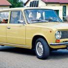 Kennzeichen: "FG G 7171". 
Ein beigefarbener, klassischer viertüriger Pkw steht auf einer gepflasterten Straße.