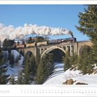 FEBRUAR. Dampflok fährt über ein Viadukt im verschneiten Wald. Schnee bedeckt die Landschaft, blauer Himmel.
