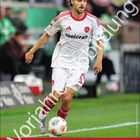 "Tom Baack", "toolcraft", "1. FCN", "Der Club", "Februar". Fußballspieler in Aktion, trägt weiß-rotes Trikot auf grünem Spielfeld.