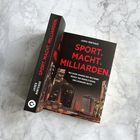 „SPORT. MACHT. MILLIARDEN.“ zeigt beleuchtete Wolkenkratzer unter dunklem Himmel auf dem Buchcover.