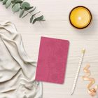 Text "2027" in goldener Schrift auf rotem Notizbuch mit floraler Prägung. Daneben eine Kerze, Bleistift und Eukalyptus.