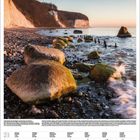 Kalenderseite Februar 2027. Große Felsen liegen am Wasser, dahinter Kreidefelsen an der Ostsee bei Sonnenuntergang.