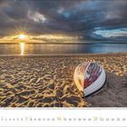 Kalender im Februar 2022. Umgekipptes Boot am Strand, Sonnenuntergang über dem Meer, dramatische Wolken.