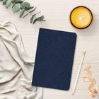 Kein Text zu lesen. Ein verziertes dunkelblaues Notizbuch, Kerze, weißes Tuch, Eukalyptuszweig, Bleistift, Schleifenband.