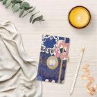 Notizbuch mit floralen Mustern und verschnörkeltem Text "an invaluable". Daneben eine Kerze, ein Stift und ein Tuch.