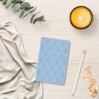 Notizbuch mit Ankern und „2027“ in der Mitte. Daneben Kerze, Eukalyptuszweig, Stoff, Stift und Schleife auf Holzuntergrund.