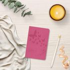 Der Text „Zauberhaft“ steht auf einem rosafarbenen Notizbuch mit Schmetterlingen. Daneben ein gelbes Kerzenglas, Stift, Band und Eukalyptus.