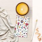 Notizbuch mit Blumenmuster und "2027", daneben eine orange Kerze, ein goldgestreifter Stift und ein beigefarbener Stoff.