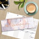 "Mein Wochenkalender 2023". Ein Tisch mit einer Tasse Kaffee, einem Kalender, Stiften und Blättern.