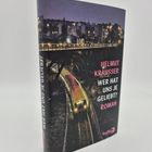 „Wer hat uns je geliebt? Roman“ von Helmut Krausser. Nachtaufnahme mit beleuchtetem Zug und Gebäuden im Hintergrund.