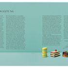 Der Text trägt den Titel "EINLEITUNG". Es folgen ausführliche Informationen über das Backen als Wissenschaft. Unten rechts sind drei Backwaren abgebildet: Macarons, eine Schichttorte und ein kleiner Obstkuchen.