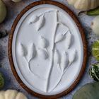 Ovaler Rahmen mit Blattrelief, umgeben von kleinen Kürbissen in verschiedenen Formen und Farben.