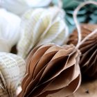 Texte auf Papierbögen. Mehrere gefaltete Papierornamente in Weiß, Braun und Grün.