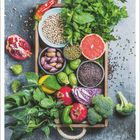 Februar. Verschiedene frische Gemüse und Obst, darunter Granatapfel, Grapefruit, Paprika und Blattgemüse auf einem Tablett.