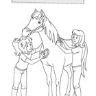 „Bibi und Tina bereiten Amadeus für ein Turnier vor. Wird er mit Tina auf dem Rücken gewinnen?“ Zwei Mädchen bürsten ein Pferd.