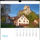 Kalender mit Monat Februar. Foto von Fachwerkhäusern und einer Burg in einer grünen, bewaldeten Landschaft.