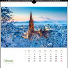 Kalender für Februar. Ein schneebedeckter Baum umrahmt eine gotische Kathedrale vor einer beleuchteten Stadt bei Dämmerung.