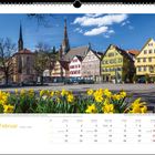 "Februar" oben über einem Platz mit Fachwerkhäusern und einer Kirche, gelbe Narzissen im Vordergrund.