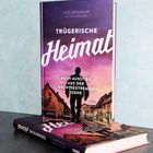 Buchtitel: "Trügerische Heimat. Mein Ausstieg aus der rechtsextremen Szene" von Leo Neuman. Silhouette vor Häuserzeile.